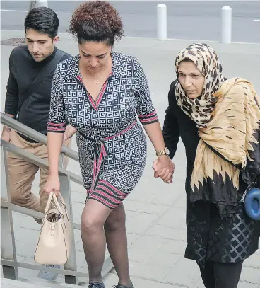  ?? JEFF McINTOSH / THE CANADIAN PRESS ?? Kobra Mohammadi, right, mother of Maryam Rashidi, and Mohamad Rashidi, left, Maryam’s brother, arrive at court for the sentencing of Joshua Cody Mitchell.