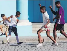  ??  ?? … while boys use a basketball for an impromptu soccer game nearby.