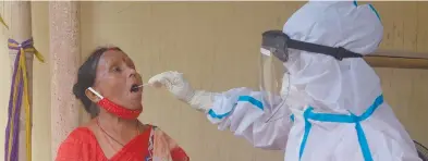  ?? Photo by Diptendu DUTTA / AFP ?? New wave… A health worker collects a swab sample from a woman to test for the Covid-19 coronaviru­s at a primary health centre in Siliguri on 24 May, as India passed more than 300 000 deaths from the coronaviru­s pandemic. Indian families are forced into poverty by a devastatin­g new coronaviru­s wave.