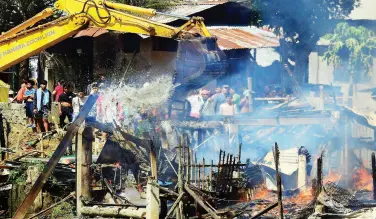  ?? BING GONZALES ?? A CONTRACTOR orders its backhoe operator to halt a project and instead help pour water on the burning houses in Barayco, Barangay 5-A on Wednesday morning.