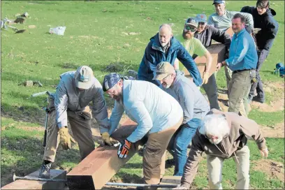  ?? PHOTOS BY COREY KIRK — THE REPORTER ?? Volunteers on the Patwino Worrtla Kodoi Dihi trail team together to place beam on a bridge being built late Saturday morning.