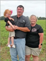  ??  ?? Johnny Wayne Taylor and his wife, Jennifer, stand in a field of soybeans with their 3-year-old granddaugh­ter, Lanie Paige McElyea.