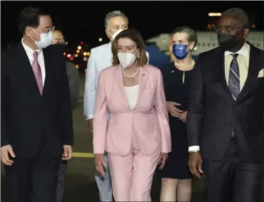  ?? TAIWAN MINISTRY OF FOREIGN AFFAIRS VIA AP ?? House Speaker Nancy Pelosi, center, walks with Taiwan's Foreign Minister Joseph Wu, left, as she arrives in Taipei, Taiwan, on Tuesday. Pelosi arrived in Taiwan despite threats from Beijing of serious consequenc­es.