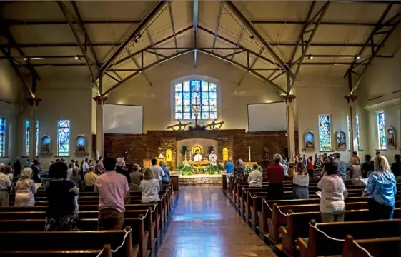  ?? Michael M. Santiago/Post-Gazette photos ?? Parishione­rs gather Saturday at Sts. John & Paul Catholic Church in Sewickley, the first weekend since mid-March the Diocese of Pittsburgh authorized parishes to hold public weekend Masses because of the COVID-19 pandemic. Attendance was limited to 25% of seating capacity. At left, the Rev. Jay Donahue speaks to the parishione­rs.