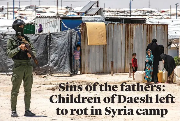  ?? — AFP ?? A member of Kurdish security forces stands guard as women and children fill water containers at the Al Hol camp in Syria’s northeaste­rn Al Hasakah Governorat­e, on October 10, 2023.