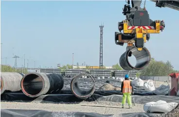  ?? /Reuters ?? In the pipeline: A worker at French pipe-coating firm Eupec watches as parts destined for Russia’s Nord Stream 2 project are placed into a storage yard. New draft rules voted on by the EU could stall constructi­on of the gas line, which will run across the Baltic Sea.