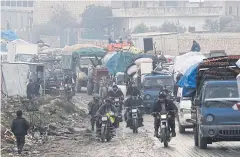  ??  ?? MASS EXODUS: Men riding motorbikes pass trucks carrying the belongings of displaced Syrians, in northern Idlib, Syria last week.