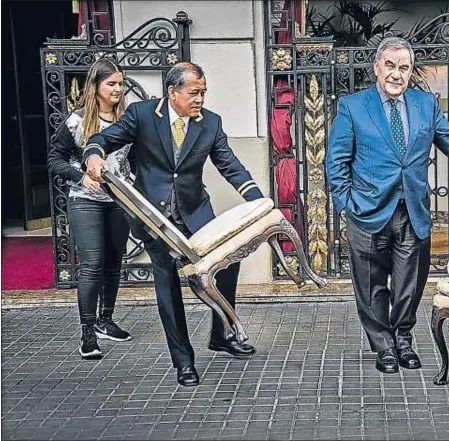  ??  ?? El porter de l’hotel Palace, Reynaldo, porta una cadira perquè Lluís Foix es fotografiï amb Víctor del Árbol