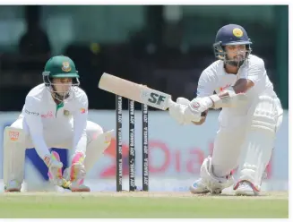  ??  ?? Sri Lanka's Dinesh Chandimal plays a shot as Bangladesh wicketkeep­er Mushfiqur Rahim watches on day one of their second Test match in Colombo on Wednesday. (AP)
