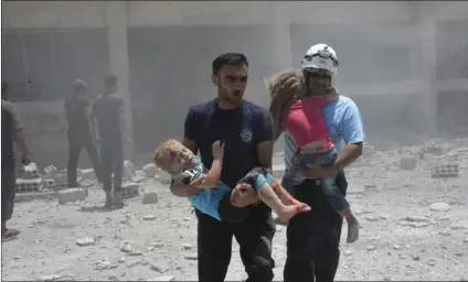  ??  ?? This photo provided by the Syrian Civil Defense group known as the White Helmets, shows civil defense workers carrying children after airstrikes hit a school housing a number of displaced people, in the western part of the southern Daraa province of...