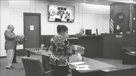  ?? PHOTO BY RANDY HOEFT/ YUMA SUN ?? RICHARD PARKS (LEFT), with the Yuma County Public Defender’s Office, and Teri Capozzi, head of the Yuma County Legal Defender’s Office, confer during Monday afternoon’s appearance of James Givens (seen standing in television screen) from the Yuma County Adult Detention Facility via video feed in Yuma Justice Court before Justice of the Peace Gregory Stewart (right). Also present are prosecutor Karolyn Kaczorowsi (center), of the Yuma County Attorneys Office, and JP1 Bailiff Helen Orman.