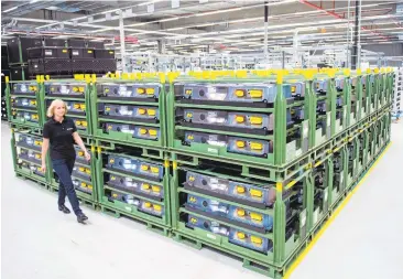  ?? ROBERT MICHAEL/AFP/GETTY IMAGES ?? An employee walks past accumulato­rs for cars at the Accumotive factory in Kamenz, eastern Germany. Large-scale factories planned for Europe are expected to cut the cost of lithium-ion packs by 43 percent and make electric cars a mainstream reality.