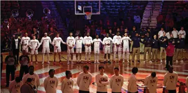  ?? DAVID JABLONSKI/STAFF ?? University of Dayton and Saint Joseph’s (foreground) players stand for the national anthem before their game in the Atlantic 10 Conference tournament March 9 in Brooklyn, N.Y. UD won the game.