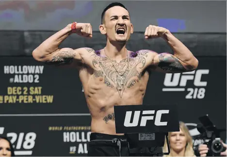  ?? JOSE JUAREZ/THE ASSOCIATED PRESS ?? UFC featherwei­ght champion Max Holloway poses for the crowd during Friday’s weigh-in for his rematch title bout against Brazil’s Jose Aldo tonight in Detroit. The Hawaiian took the title from Aldo earlier this year.