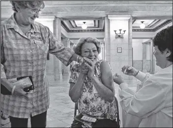 ?? LAURIE SKRIVAN / AP PHOTO ?? Carol Evans (left) offers a comforting hand to co-worker Dusty Reese as nurse Kandie Halleran administer­s Reese a flu shot in the main lobby rotunda area of City Hall on Oct. 24 in St. Louis.