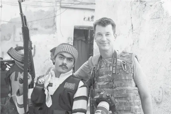  ?? THE ASSOCIATED PRESS FILES ?? Freelance British photojourn­alist John Cantlie poses with a Free Syrian Army rebel in Aleppo in 2012. He was taken hostage by extremists the same year.