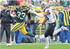  ?? DAN POWERS, WISCONSIN-USA TODAY SPORTS ?? Packers running back Aaron Jones (33) stiff-arms Saints cornerback Marshon Lattimore (23). Jones carried a heavy load for Green Bay.