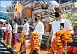  ?? AP Photo/ Firdia Lisnawati ?? Airport officers wearing face masks line up as they hold flowers to welcome passengers July 31 at the airport in Bali, Indonesia. The resort island has reopened to domestic tourists after months of lockdown due to a new coronaviru­s.