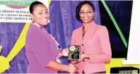  ??  ?? Kamisue Mills (left) collects her award from Kishma Simpson, acting senior director, Jamaica Library Service.