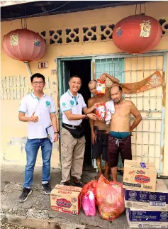  ??  ?? Hope Place founder Kelvin Wan (second left) hands over food items to the Jong brothers.