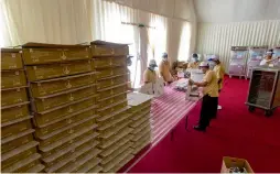  ??  ?? Volunteers pack meals to be distribute­d among the faithful in one of the 12 air-conditione­d tents at the mosque; and (right) people end their fast after the cannon is fired.