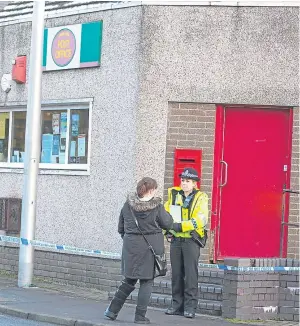  ??  ?? A police officer stands on duty outside the post office at Kinglassie after the masked raider struck.