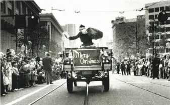  ?? Fred Larson / The Chronicle 1982 ?? The Emporium’s Santa Claus rides down Market Street during a holiday parade.