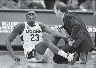  ?? JESSICA HILL/AP PHOTO ?? UConn’s Akok Akok (23) reacts while tended to by head trainer James Doran in a game against Memphis on Feb. 16 in Hartford.