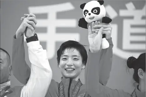  ?? XINHUA ?? Karateka Yin Xiaoyan celebrates winning the kumite -61kg category at the 14th National Games in Xi’an on Saturday. Yin, 28, won China’s first-ever Olympic karate medal — a silver — in Tokyo, and retained her national title with a 6-0 triumph.