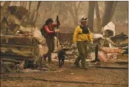  ?? HECTOR AMEZCUA—ASSOCIATED PRESS ?? Butte County Search and Rescue worker Noelle Francis, left, and search dog Spinner look through the ashes for survivors and remains after a wildfire ravaged the area, at Skyway Villa Mobile Home and RV Park in Paradise, Calif., Monday, Nov. 12, 2018.