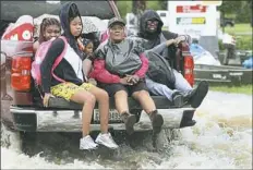  ??  ?? People escape from a flooded neighborho­od Tuesday following Hurricane Harvey.