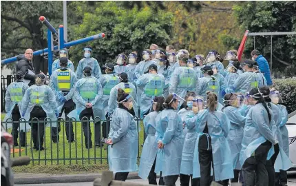  ??  ?? Police and nurses wearing protective equipment outside tower blocks in north Melbourne in Australia.