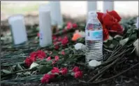  ?? The Associated Press ?? MEMORIAL: A bottle of water, flowers, candles and stuffed animals help form a makeshift memorial Monday in the parking lot of a Walmart store near the site where authoritie­s Sunday discovered a tractor-trailer packed with immigrants in San Antonio.