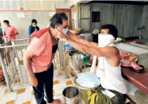  ??  ?? A TEMPLE PRIEST offers a mask as “prasad” to a devotee on the first day of the Hindu holy month of Shravan, in Ahmedabad on July 21.