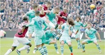  ??  ?? Rice (centre) jumps highest but heads the ball narrowly wide during the match between West Ham United and Arsenal. — AFP photo