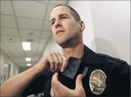  ??  ?? OFFICER JIM STOVER demonstrat­es the body camera. Concerns remain about who will get to see videos from the cameras.