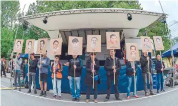  ??  ?? Protesters hold up signs with pictures of the victims of neo-nazi cell National Socialist Undergroun­d before the proclamati­on of sentence in the trial against Beate Zschaepe on Wednesday. — AFP