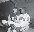 ?? THE ASSOCIATED PRESS FILE ?? Satchel Paige talks with Bob Feller in the dugout before a game July 7, 1948.