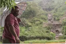  ??  ?? A man watches the landslide of mud and rocks of a hill that has partially blocked a highway in front of his house during the rains in San Marcos, El Salvador.