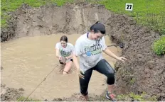  ??  ?? Lorissa Schmidt, right, and Jane Gibson, left, climb out of a mud hole at the fifth annual Pelham Mudfest Challenge on Saturday