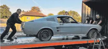  ?? FOTOS: DPA ?? Helfer rollen einen frisch importiert­en Ford Mustang aus dem Container.