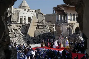  ?? The Associated Press ?? ■ Pope Francis, surrounded by shells of destroyed churches, leads a prayer Sunday for the victims of war at Hosh al-Bieaa Church Square, in Mosul, Iraq, once the de-facto capital of IS. The long 2014-2017 war to drive IS out left ransacked homes and charred or pulverized buildings around the north of Iraq, all sites Francis visited on Sunday.