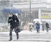  ?? AFP ?? People cross the street as it snows in the city of Toyama, Toyama prefecture on the central-western coast of Japan, yesterday.