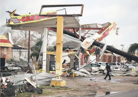  ?? — AFP photo ?? A police officer walks through a damaged gas station along Chef Menture Avenue after a tornado touched down in the eastern part of the city in New Orleans, Louisiana.