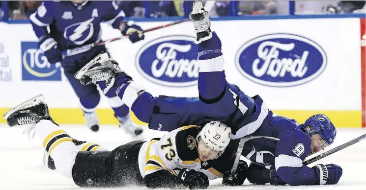  ?? MIKE EHRMANN/GETTY IMAGES ?? Tyler Johnson of the Tampa Bay Lightning, top, fights for the puck with the Boston Bruins’ Charlie McAvoy in Game 2 of their series on Monday in Tampa, Fla.