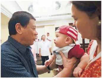  ??  ?? President Duterte plays with his grandson as his daughter Davao City Mayor Sara Duterte-Carpio looks on during an event at the Manila Hotel the other day.