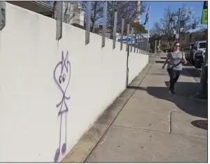  ?? ?? A pedestrian walks past graffiti Thursday on Dickson Street in Fayettevil­le.
(NWA Democrat-Gazette/J.T. Wampler)