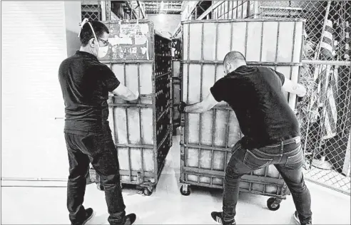  ?? AMY BETH BENNETT/SOUTH FLORIDA SUN SENTINEL PHOTOS ?? Workers move racks full of vote-by-mail ballots to be loaded onto trucks July 9 at the Broward County Voter Equipment Center in Lauderhill, Florida.