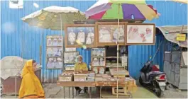  ??  ?? A Bohra woman walking past a roadside shop selling photograph­s of former Dawoodi Bohra community spiritual leader Syedna Mohammed Burhanuddi­n in the Bhendi Bazaar area that is being redevelope­d under the Cluster Developmen­t Act 2009 by the Saifee...