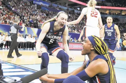  ?? ANDY LYONS/GETTY ?? Connecticu­t’s Paige Bueckers, top, and Aaliyah Edwards celebrate after a play in the fourth quarter against Stanford during an NCAA women’s semifinal Friday night in Minneapoli­s. Bueckers finished with 14 points in the Huskies’ 63-58 victory.
